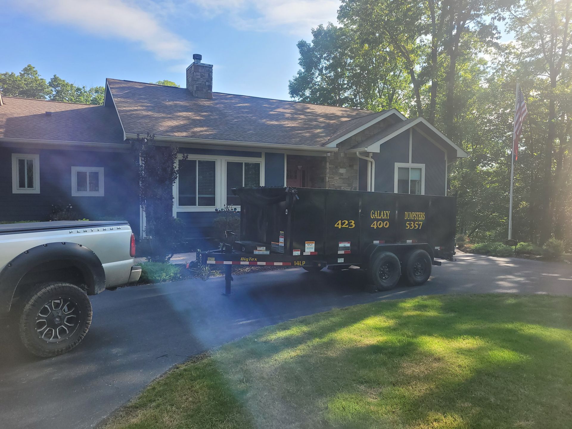 A truck and trailer are parked in front of a house.