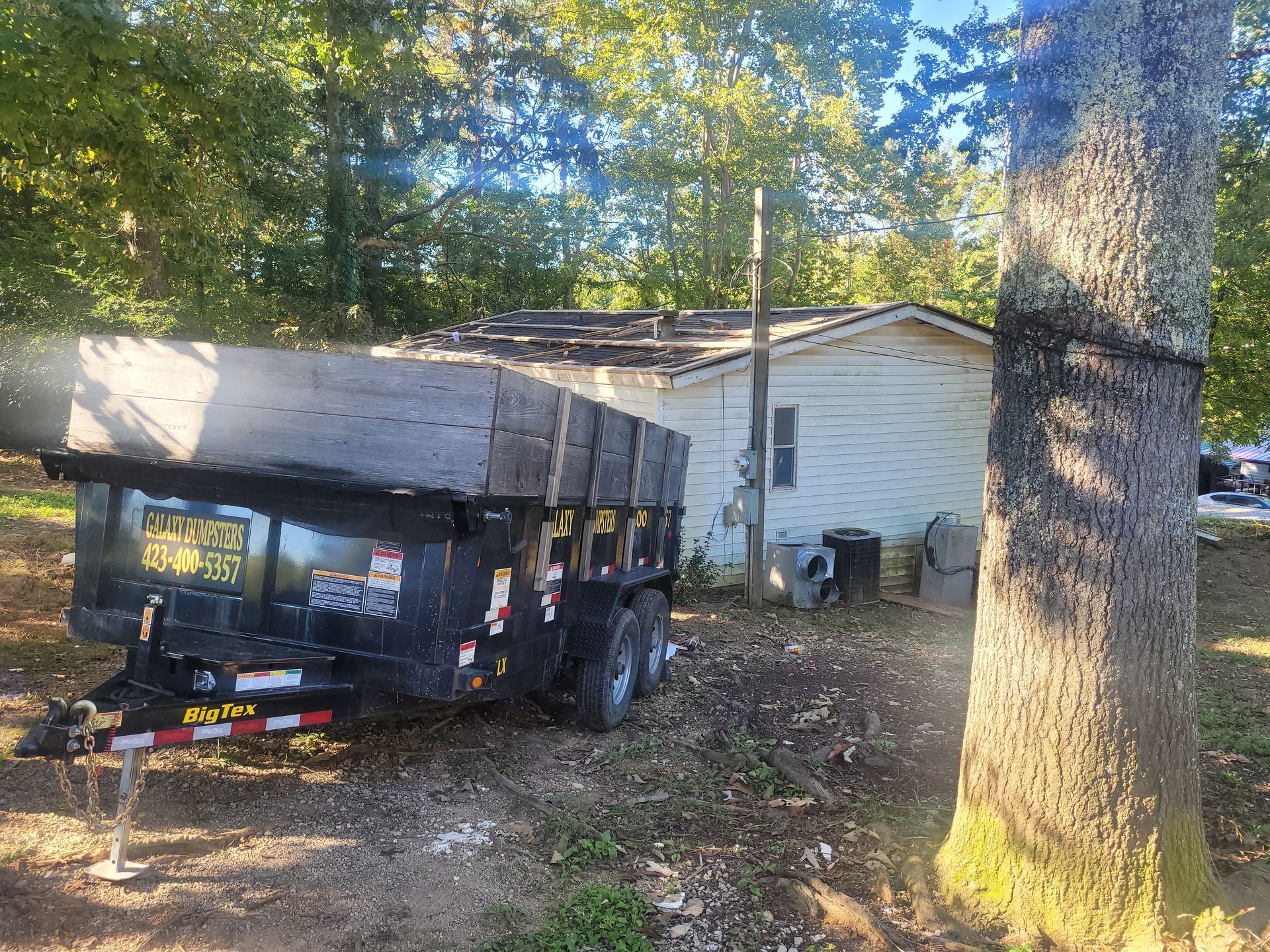 A dumpster trailer is parked in front of a house.