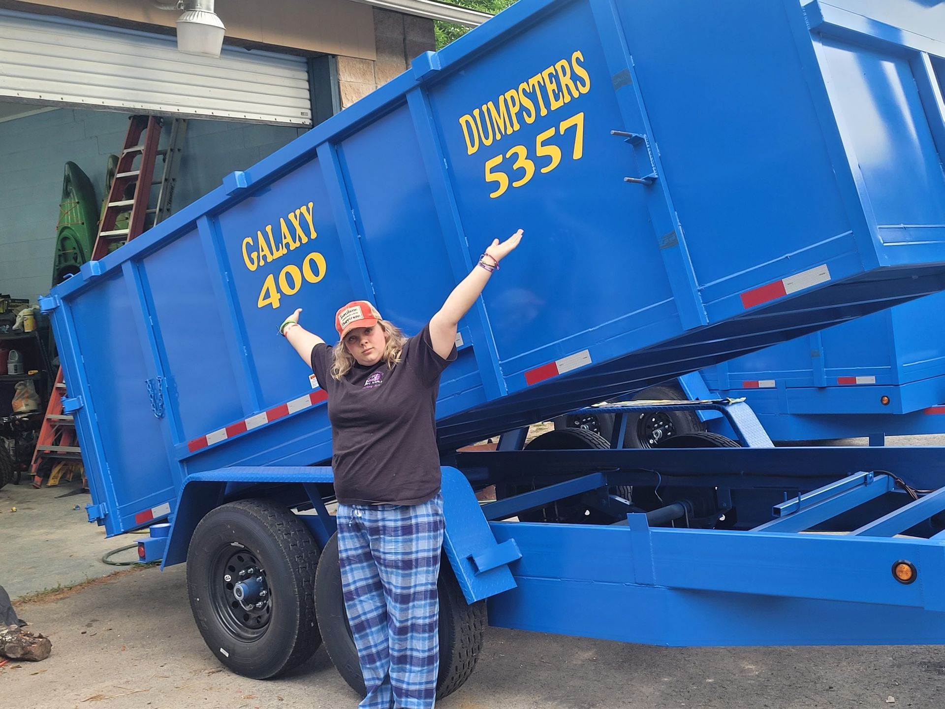 A woman is standing in front of a blue dumpster that says galaxy 400