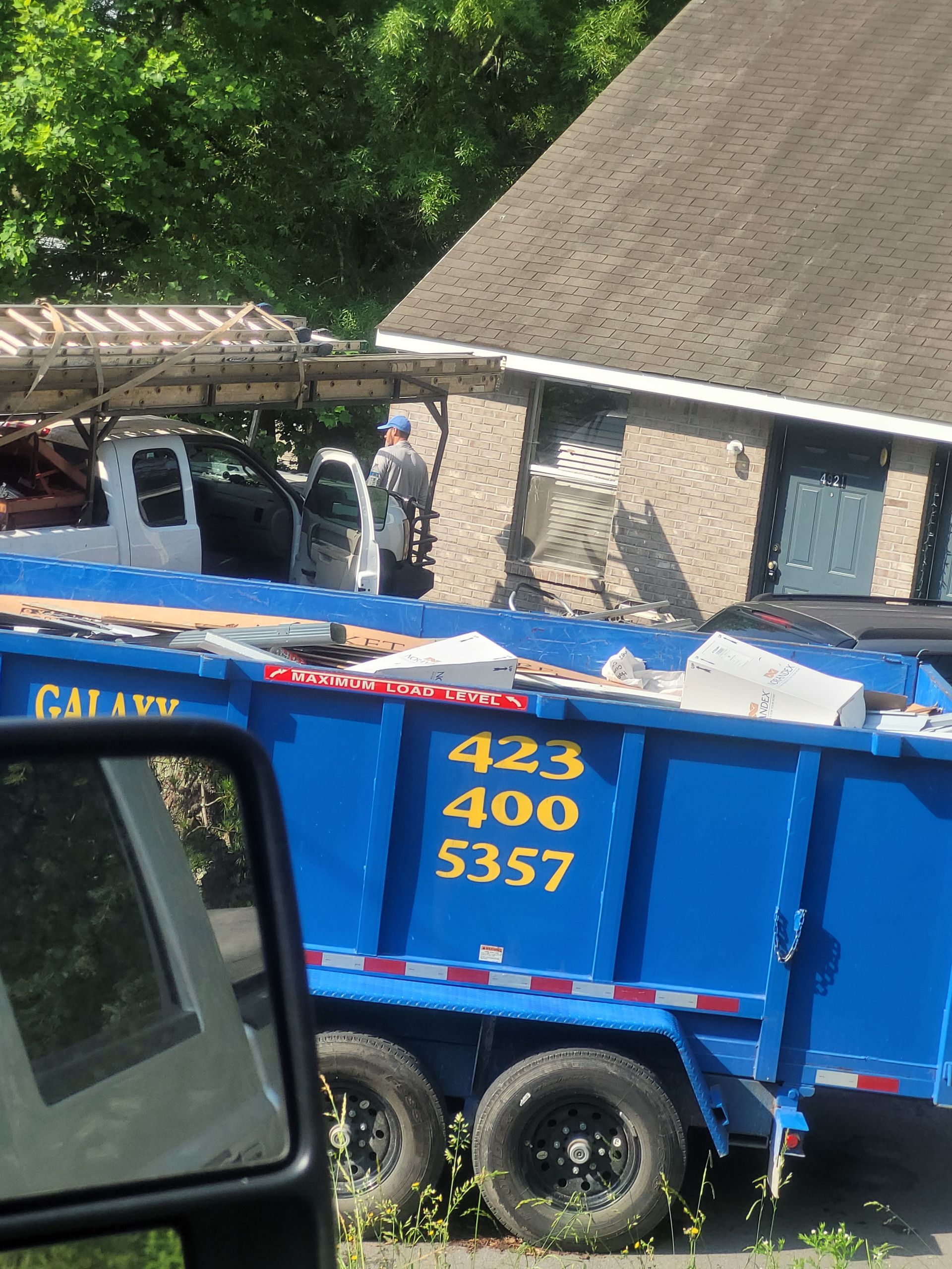 A blue dumpster with the number 433 400 5357 on it