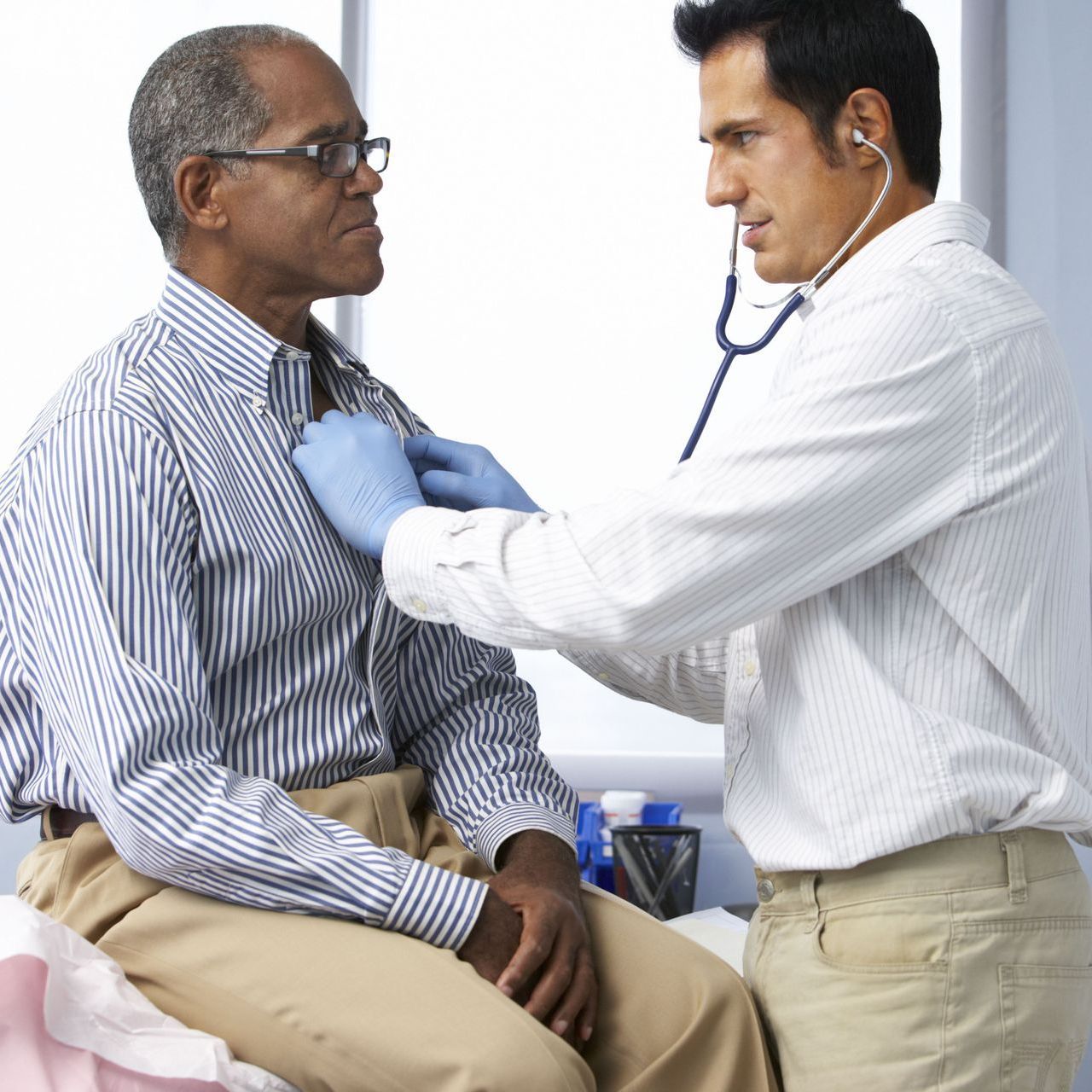 A doctor is listening to a patient 's chest with a stethoscope.