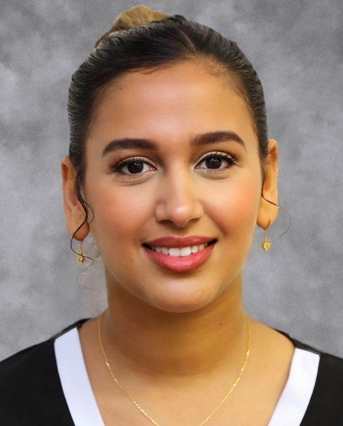 A woman wearing a necklace and earrings smiles for the camera