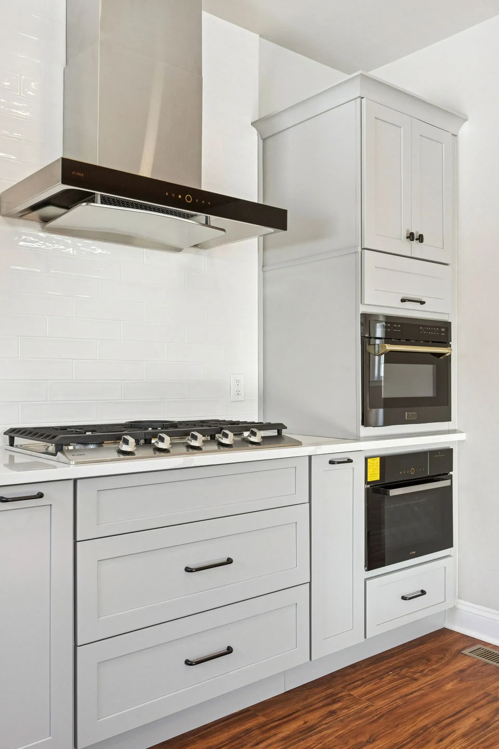 Modern white kitchen with gas cooktop, built-in oven, and tall cabinets