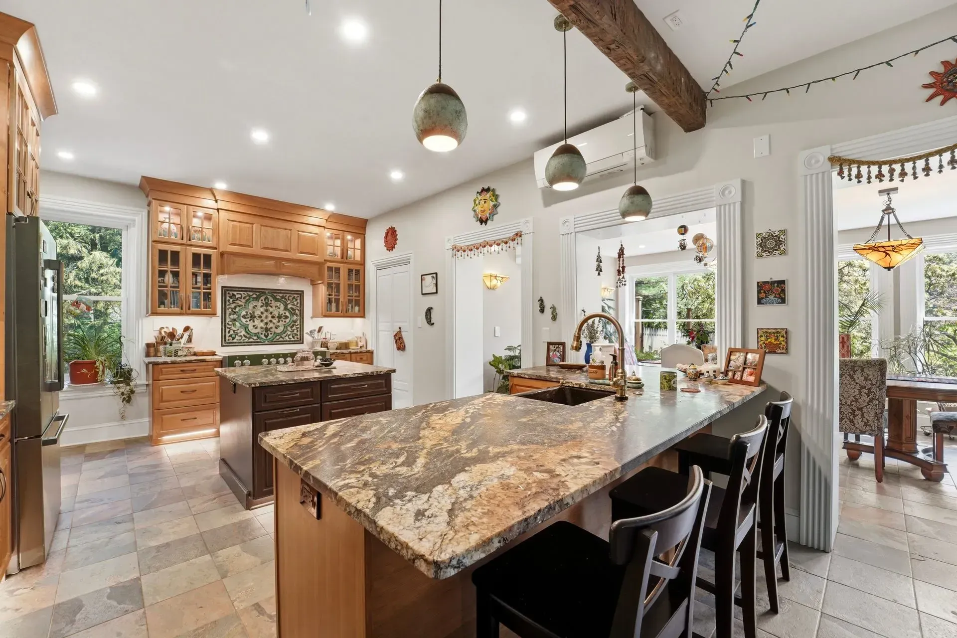 Bright modern kitchen with granite island, wood beams, white cabinets, and pendant lights