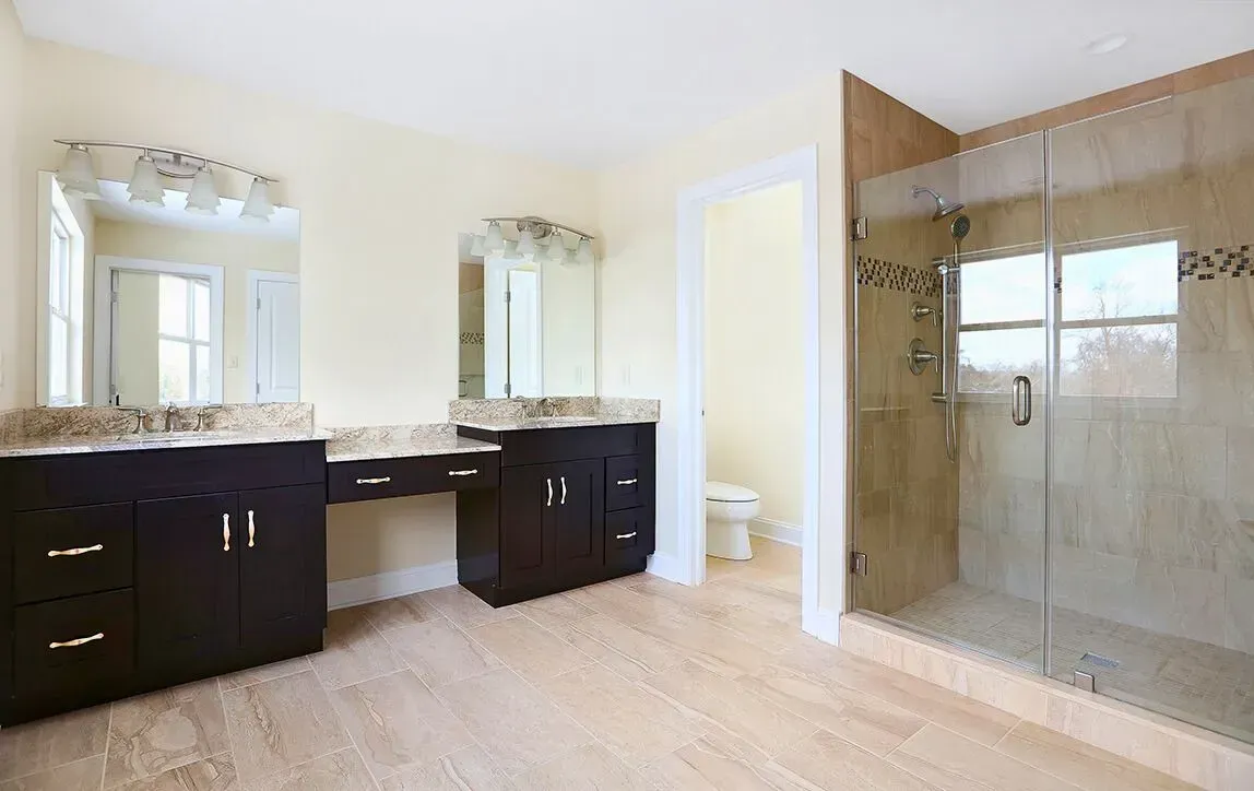 Bright bathroom with dark vanity, large mirror, granite countertop, and glass walk-in shower.