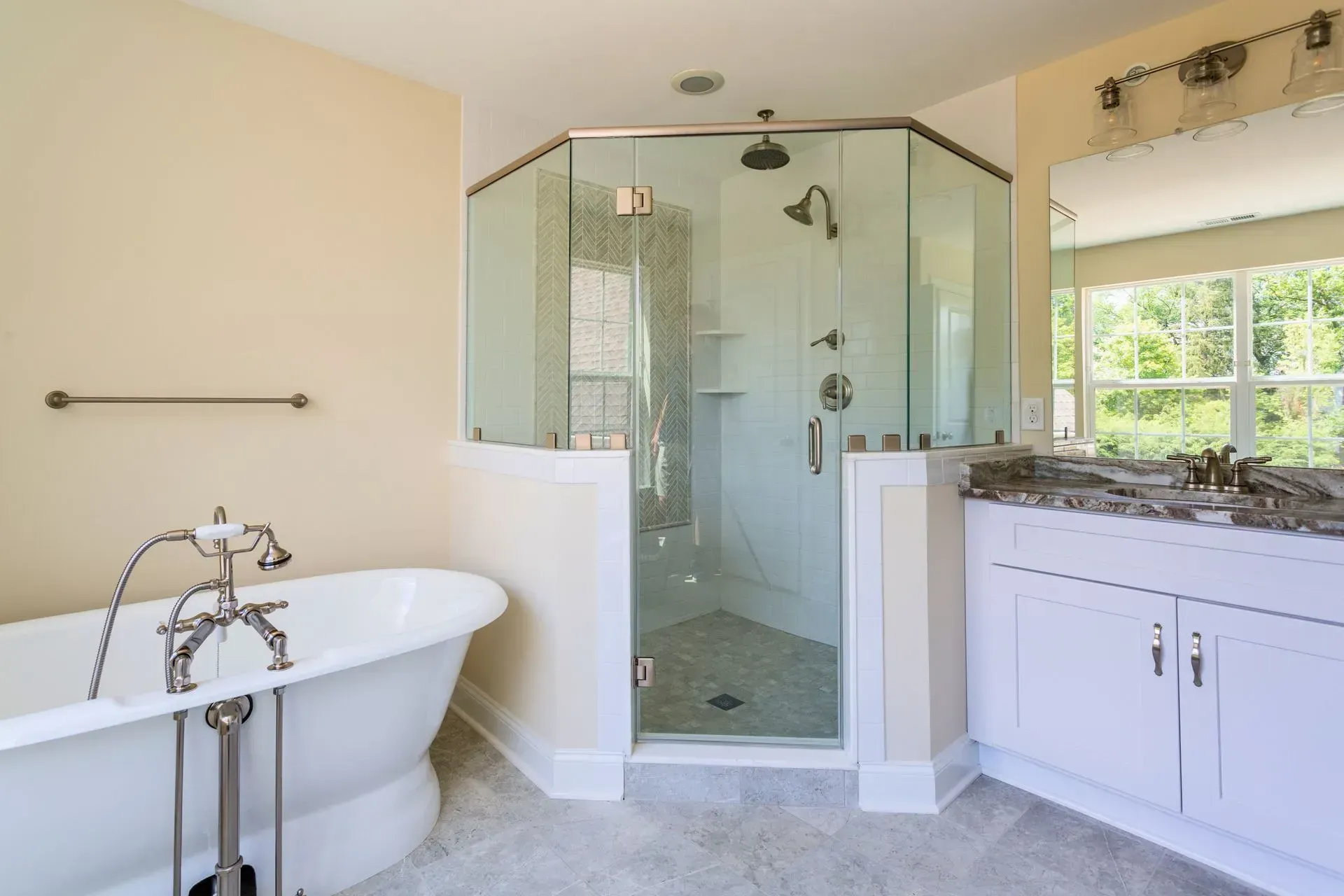 Modern bathroom with freestanding tub, glass shower, and white vanity near a window
