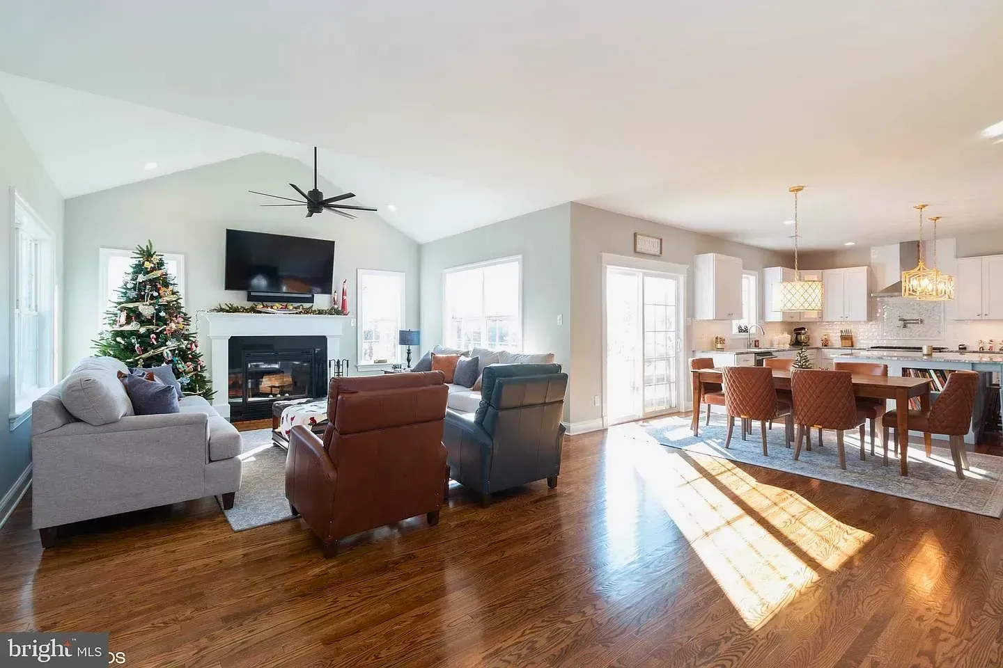 Open living and dining room with fireplace, Christmas tree, and bright hardwood floors