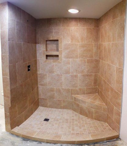 A tiled shower with a corner seat and a shelf.