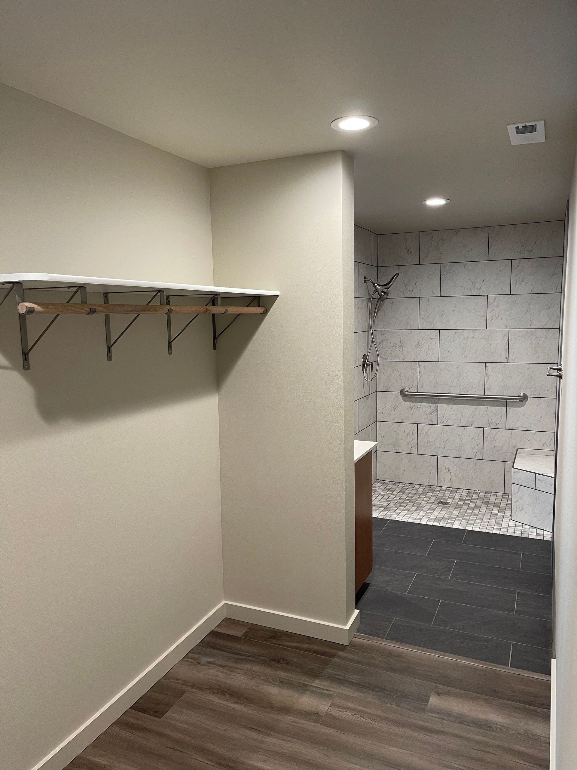 An empty room with a shelf on the wall and a wooden floor.