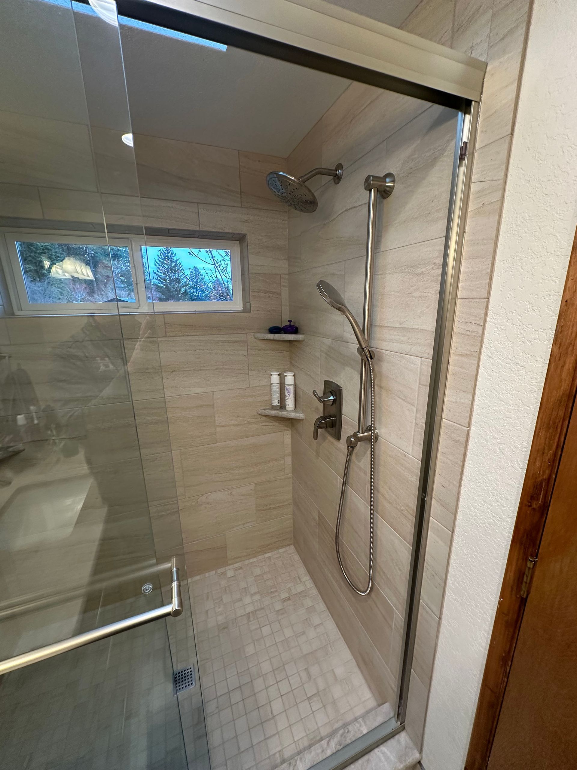 A bathroom with a walk in shower and a window.