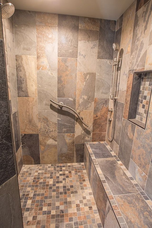 A walk in shower with a bench and a hand rail.