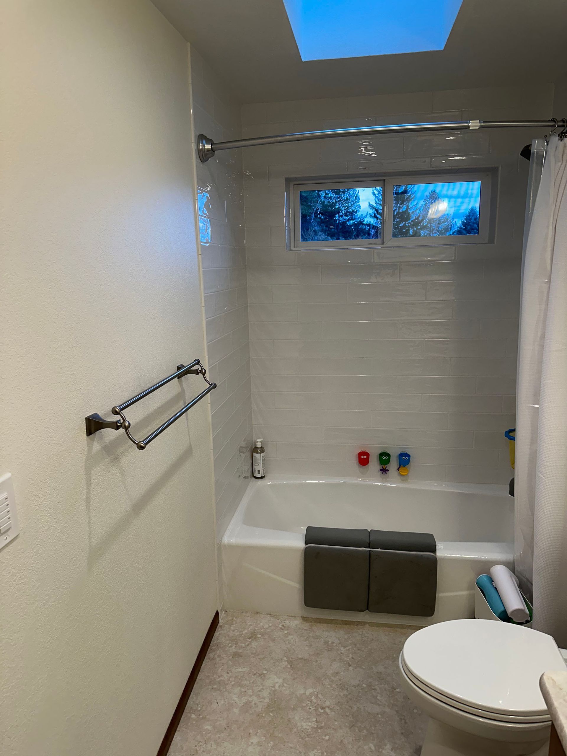 A bathroom with a toilet , tub , shower and skylight.