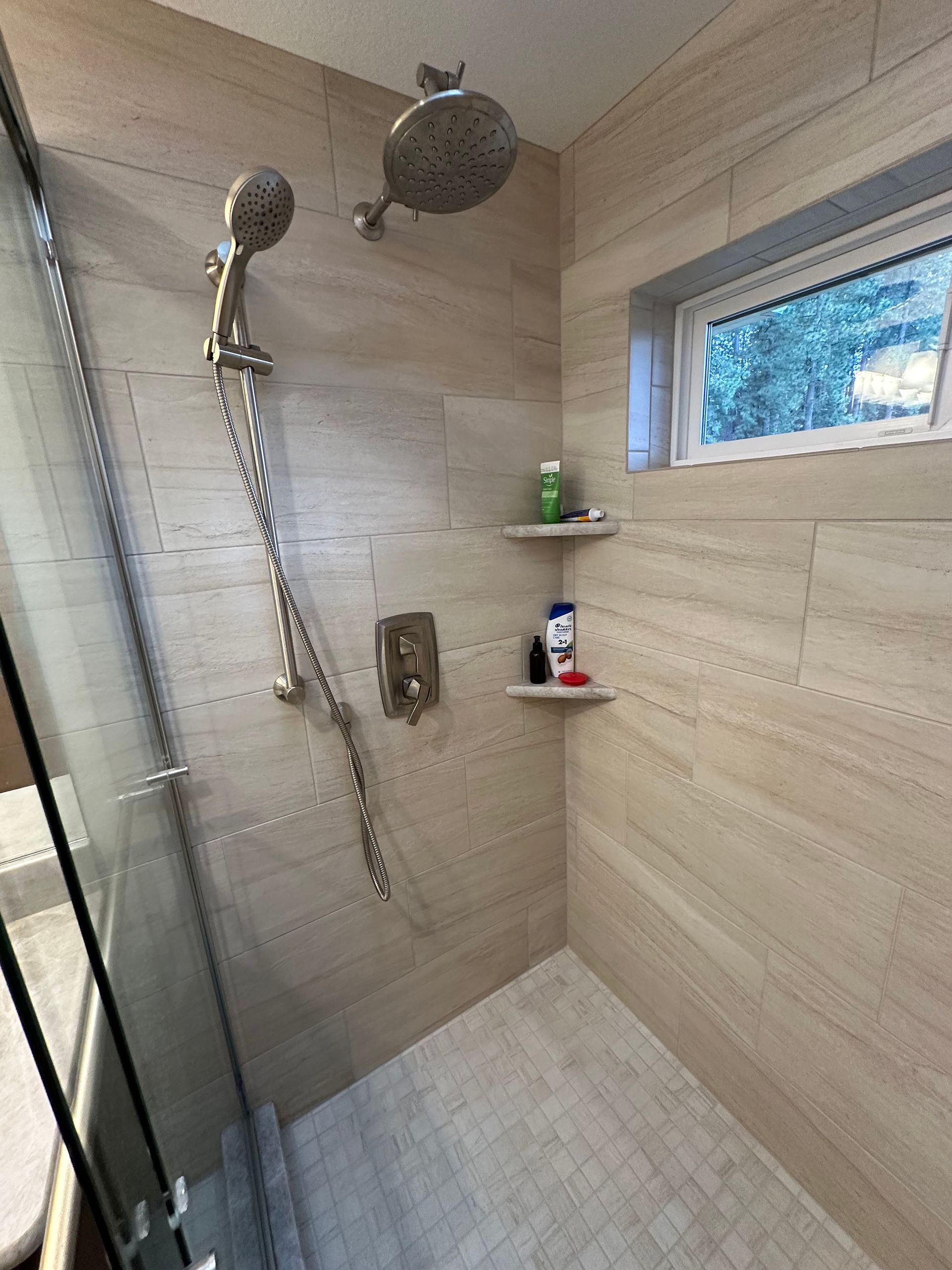 A bathroom with a walk in shower and a window.