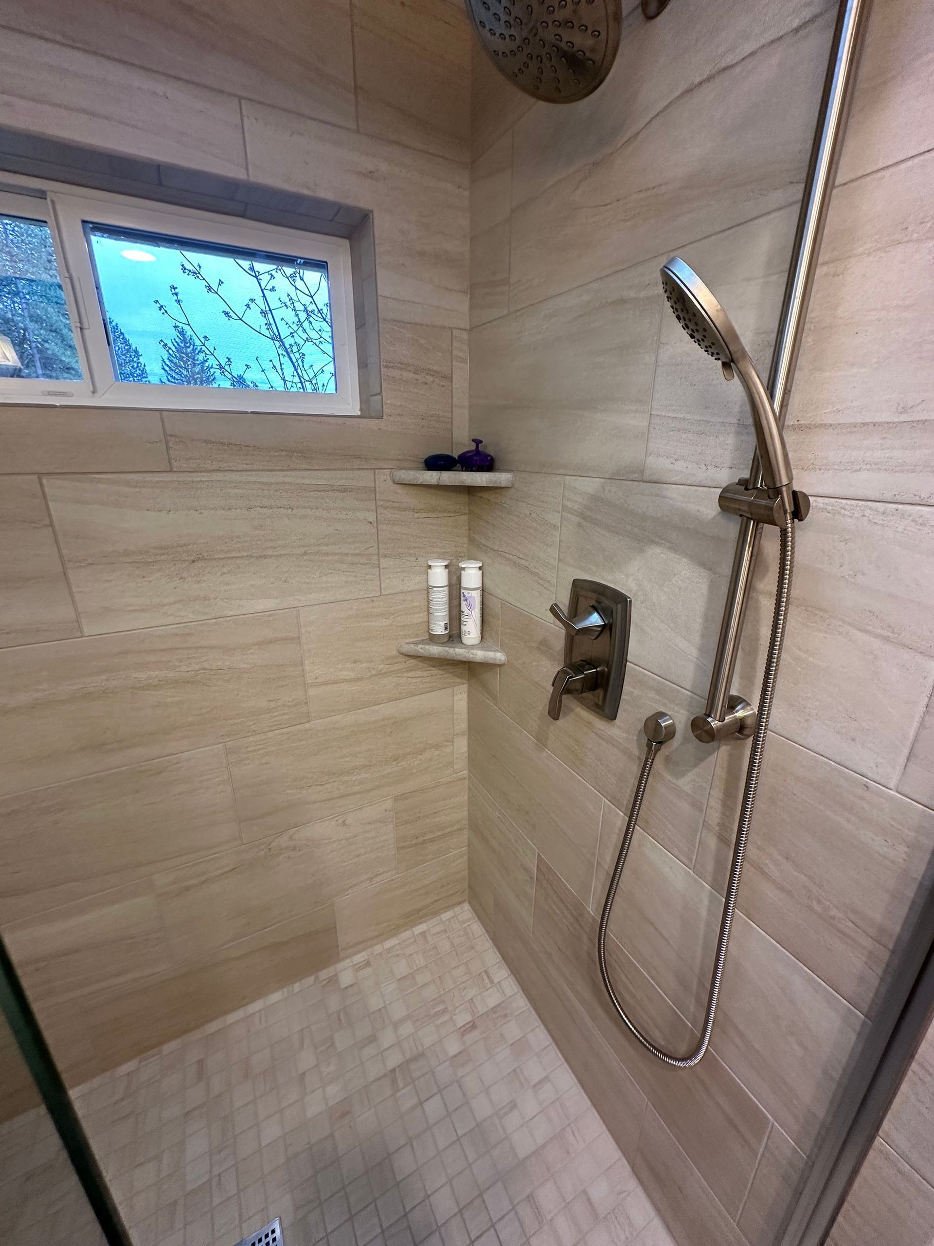 A walk in shower with a window and a shower head.