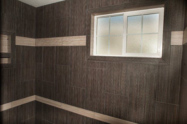 A bathroom with brown tile walls and a window.