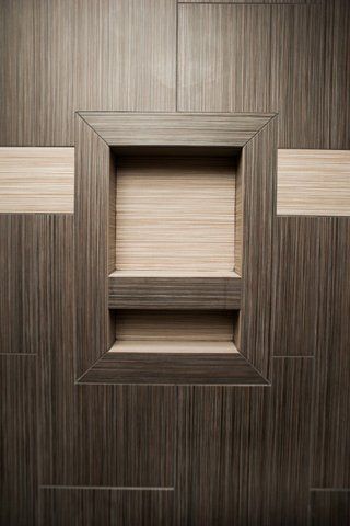 A close up of a wooden wall with a shelf in it.