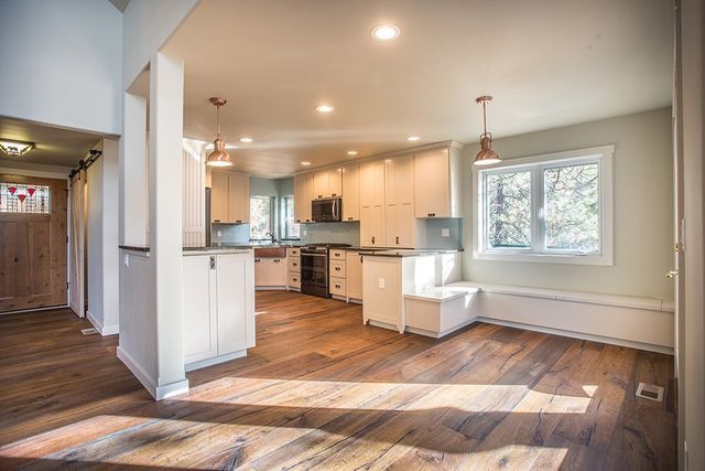 A kitchen and dining room in a house with hardwood floors and white cabinets.