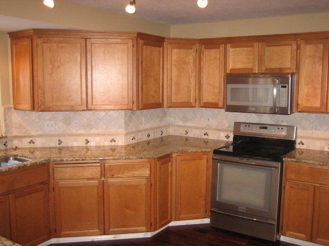 A kitchen with wooden cabinets stainless steel appliances and granite counter tops