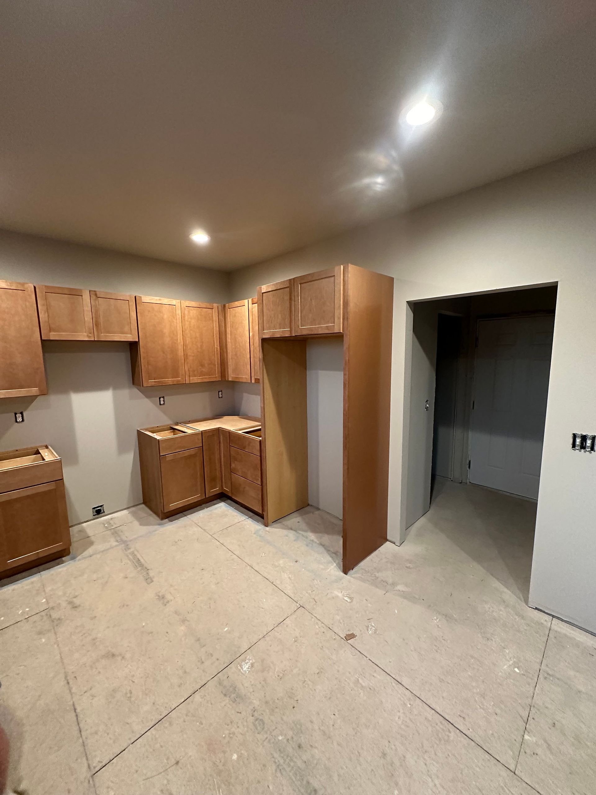 A kitchen with wooden cabinets , stools , a table and a microwave.