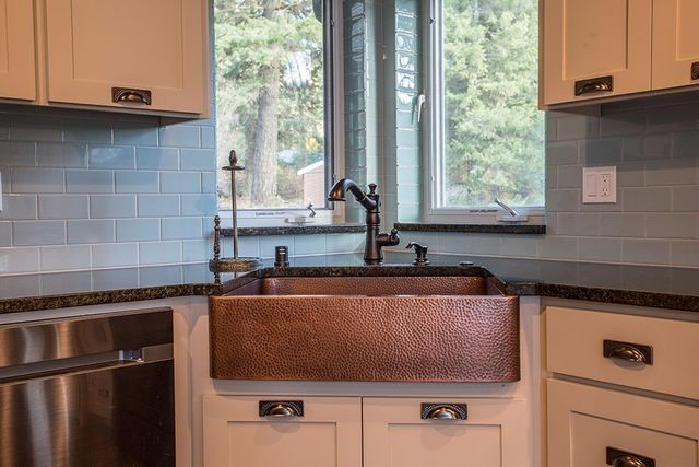 A kitchen with a copper sink and stainless steel appliances.