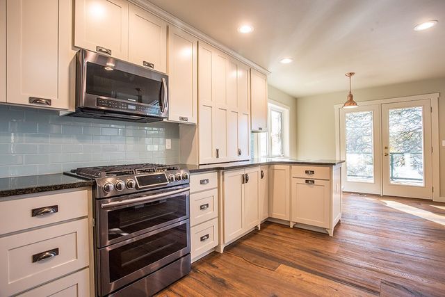 A kitchen with white cabinets , stainless steel appliances , and hardwood floors.
