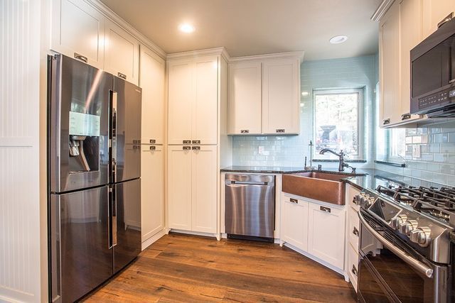 A kitchen with stainless steel appliances and white cabinets.