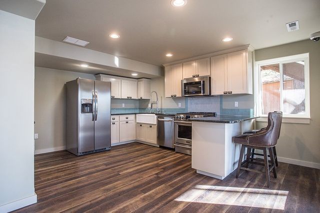 A kitchen with stainless steel appliances and wooden floors.