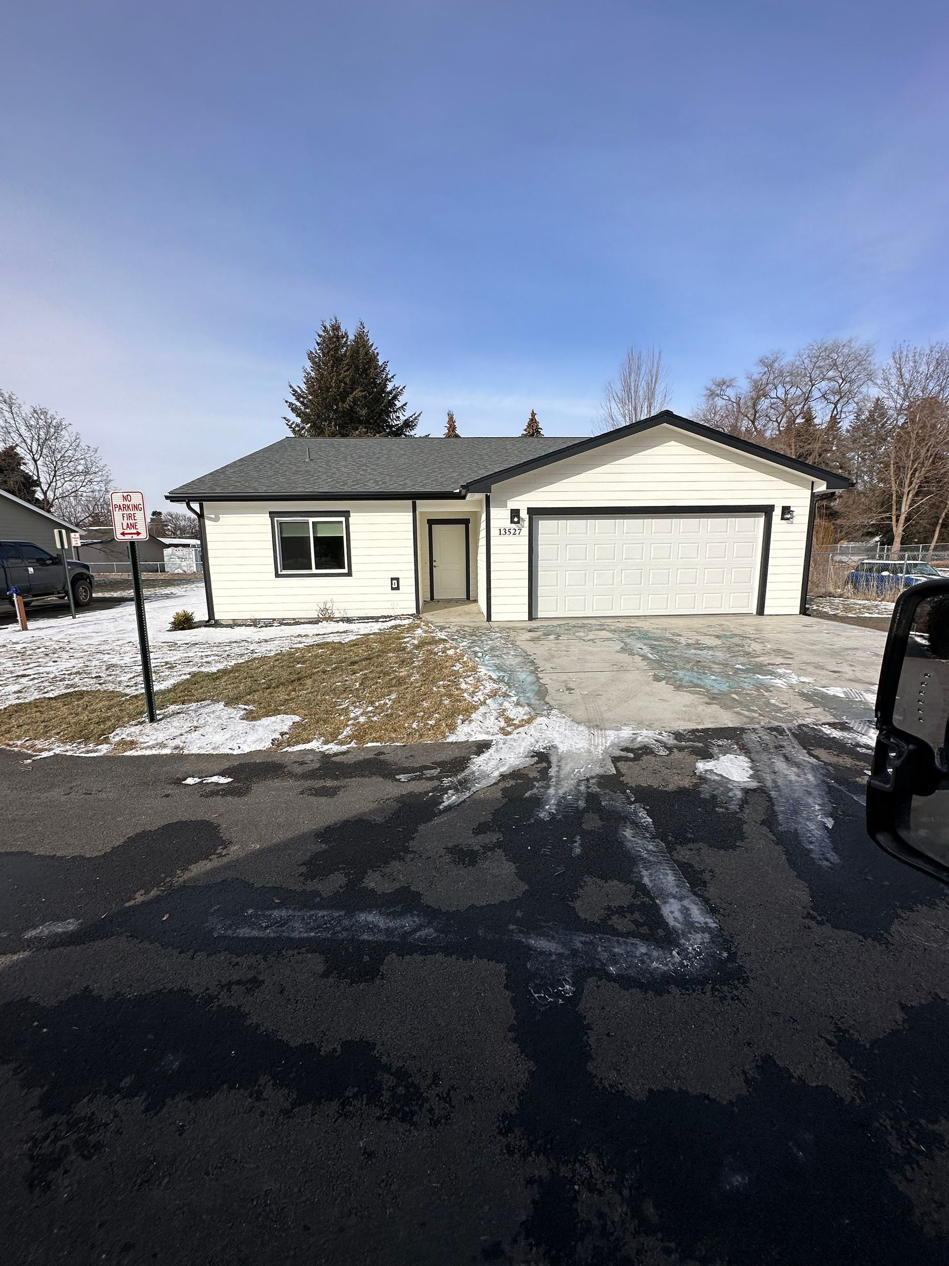 A white house with a garage and a no parking sign in front of it.