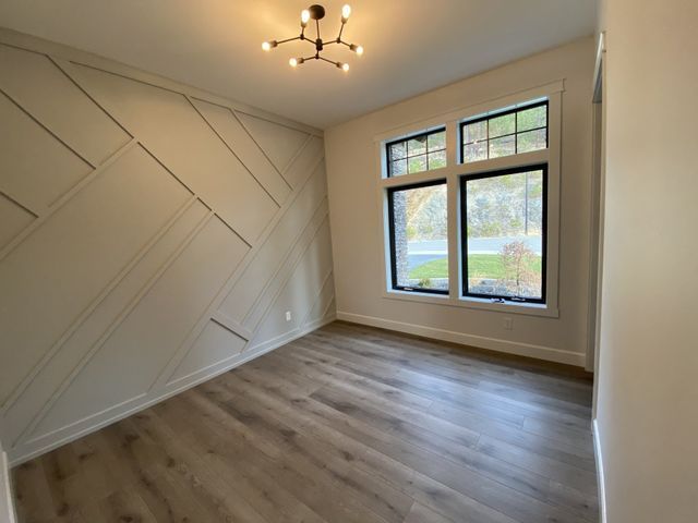 An empty room with hardwood floors and two windows