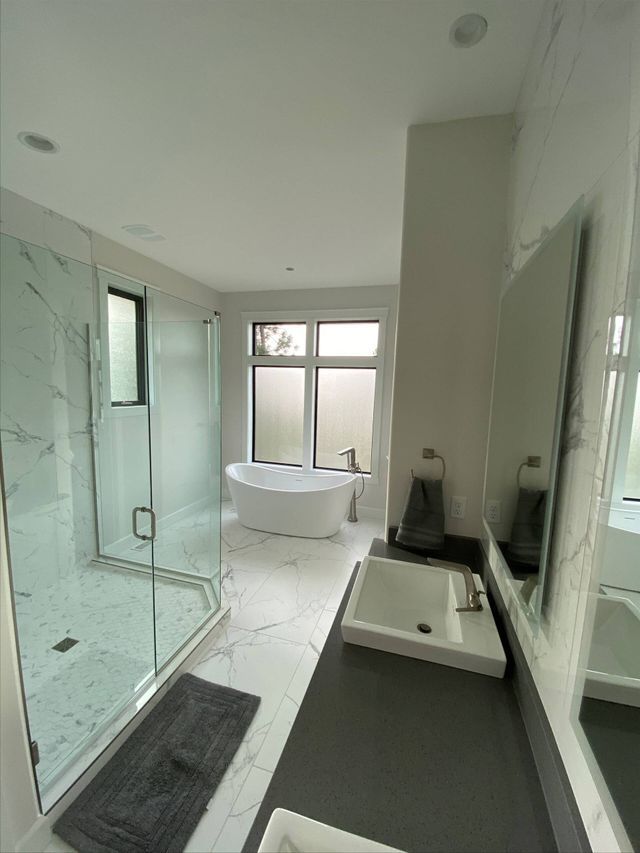 A bathroom with a tub , sink , shower and mirror.