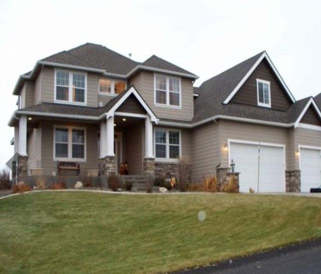 A large house with two garages sits on a lush green hillside