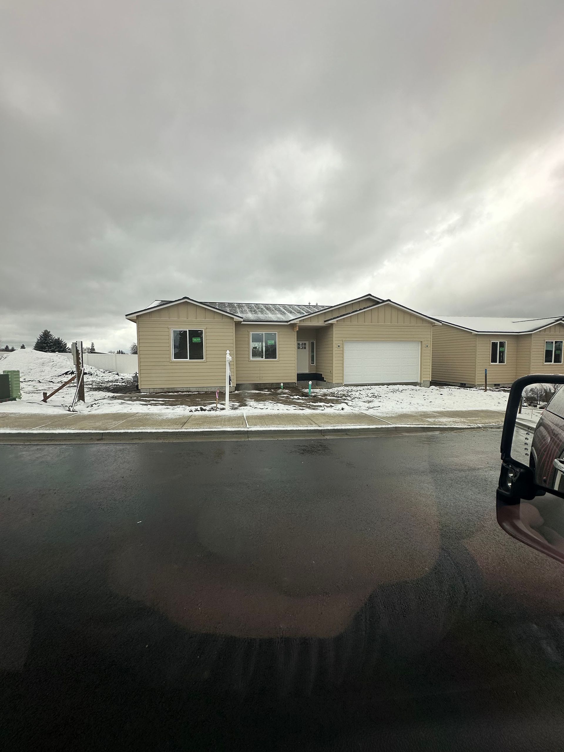 A car is parked in front of a house with snow on the ground.