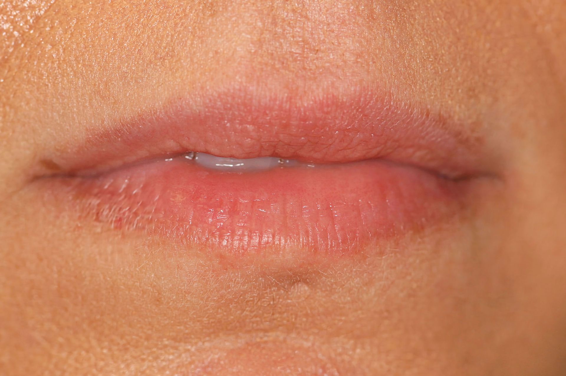Close-up of human lips, slightly open, with a thin line of saliva visible. Pinkish skin.