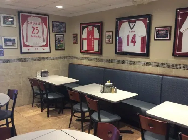A restaurant with tables and chairs and framed jerseys on the wall