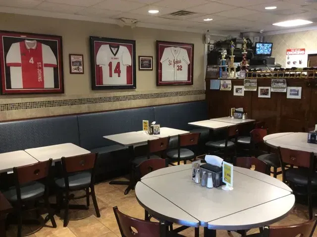 A restaurant with tables and chairs and jerseys on the wall including one that says 14