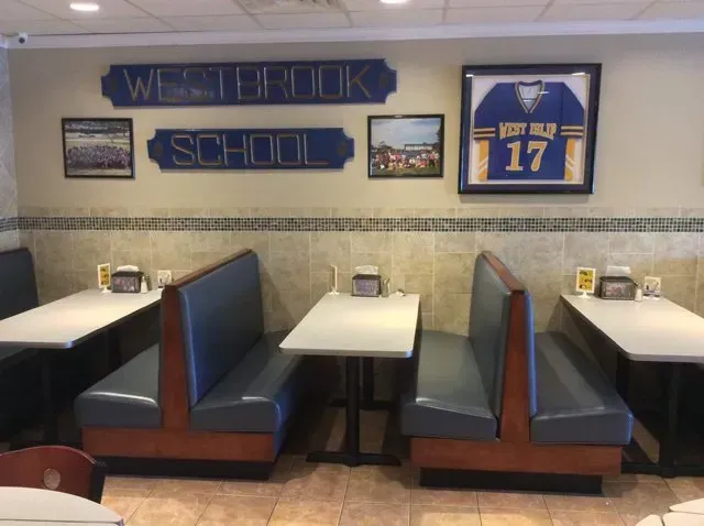 A restaurant with tables and benches and a sign that says westbrook school