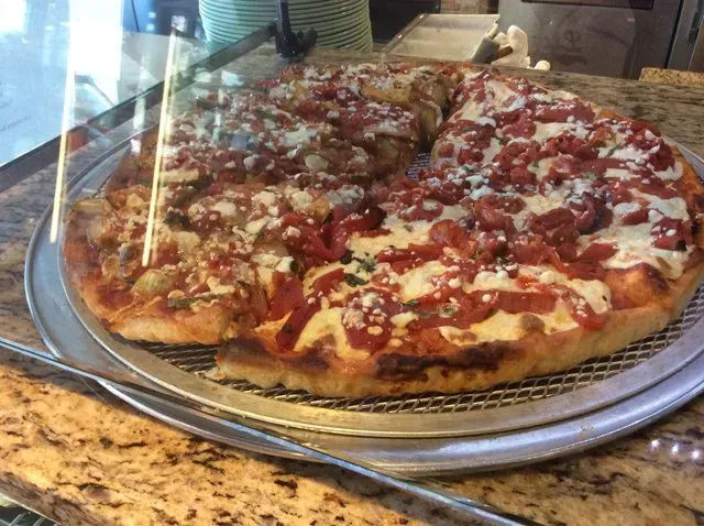 A pizza is sitting on a metal pan on a counter.