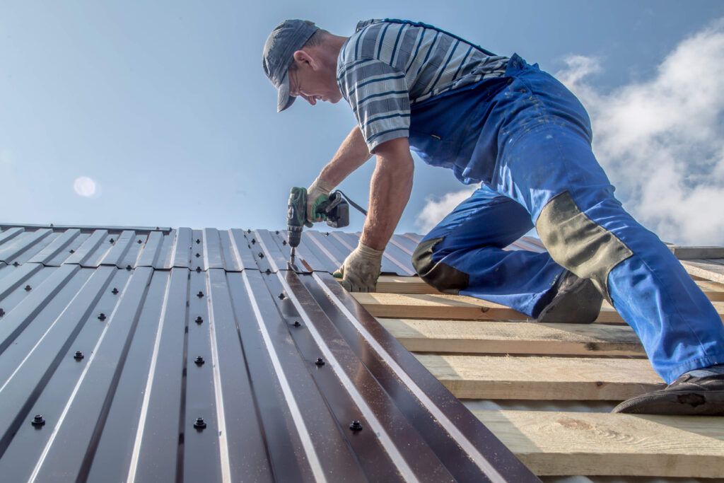 A man is installing a metal roof on a house.