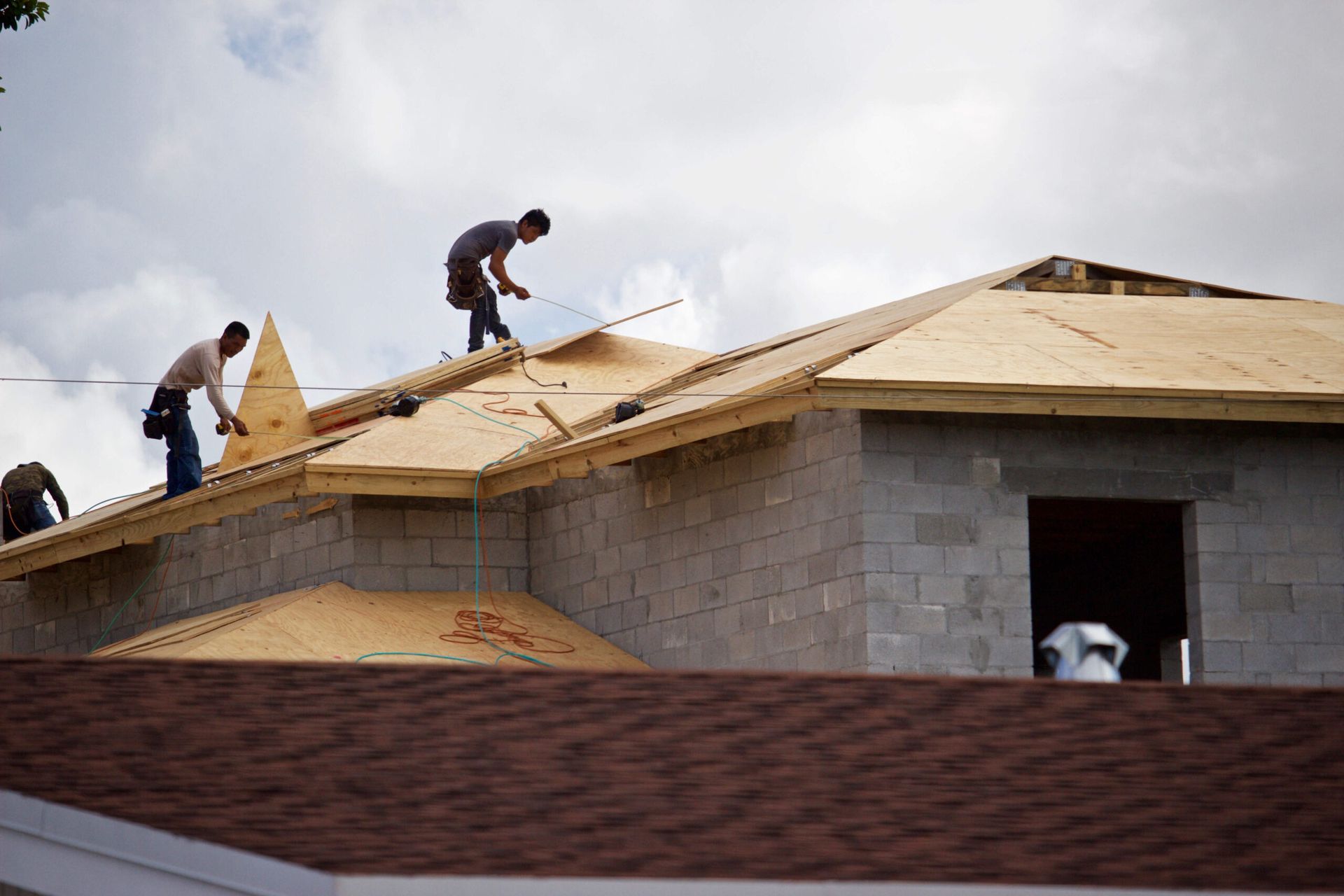 A group of men are working on the roof of a house.