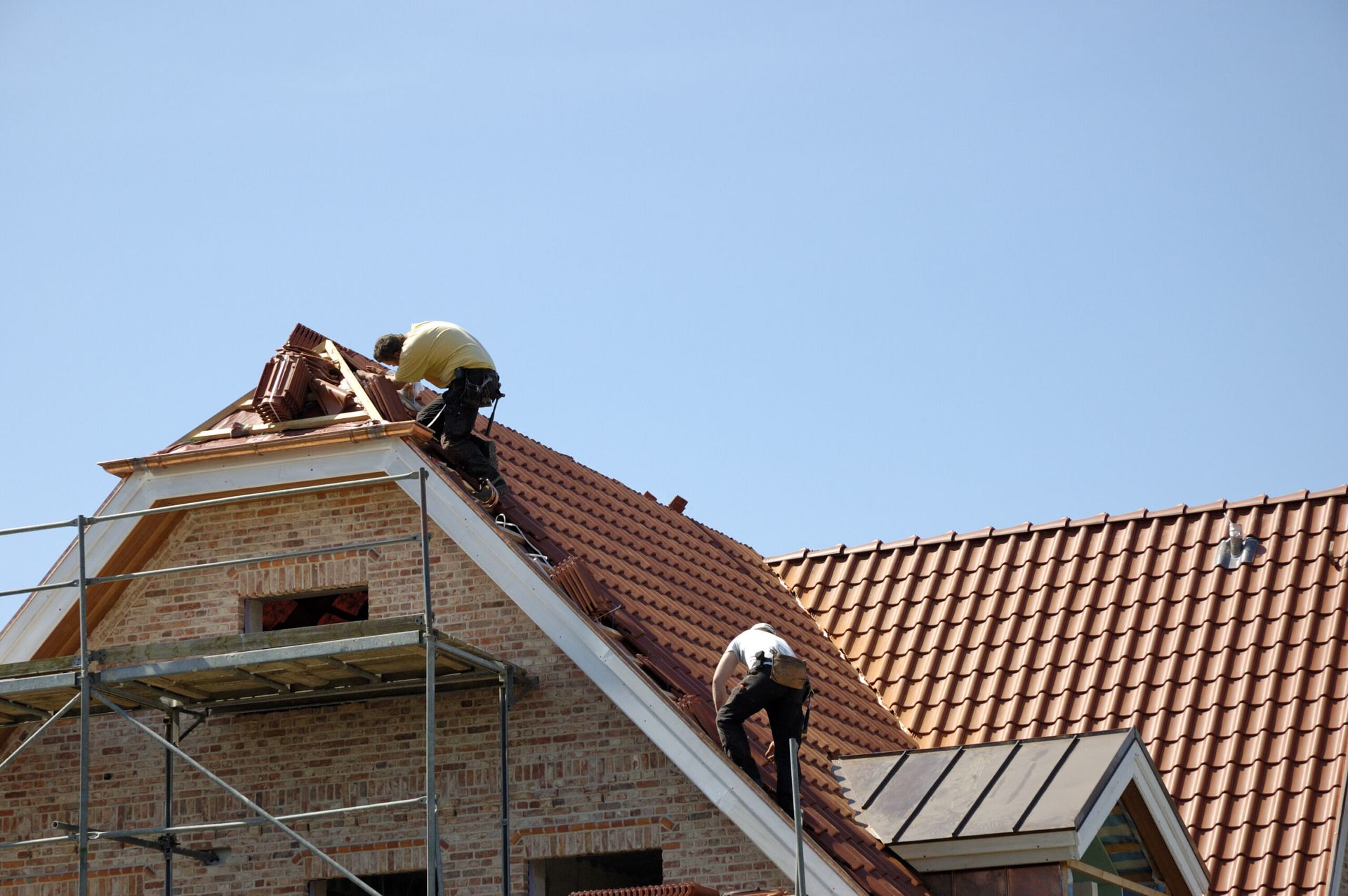 Two men are working on the roof of a building.