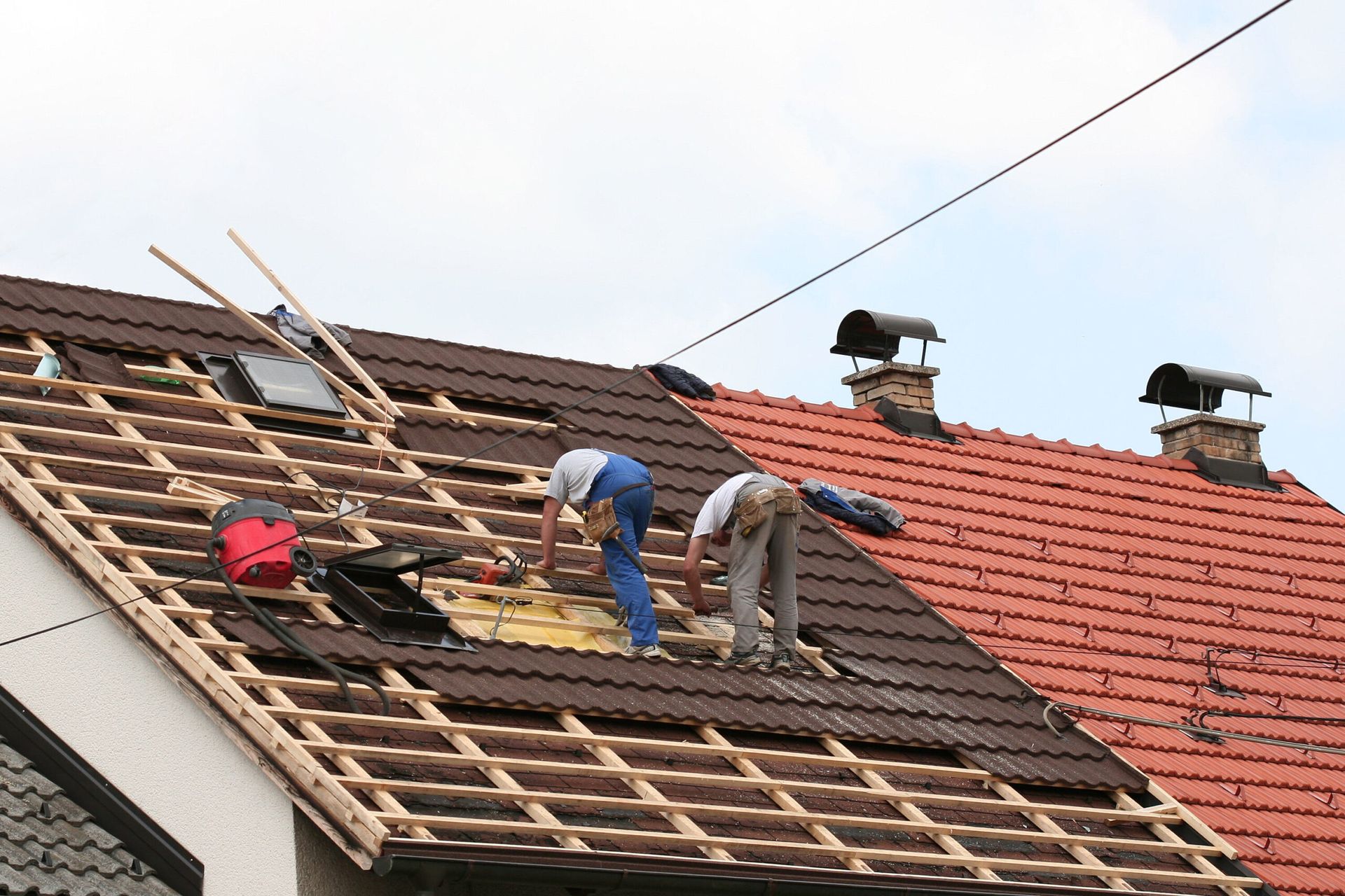 Two men are working on the roof of a house.