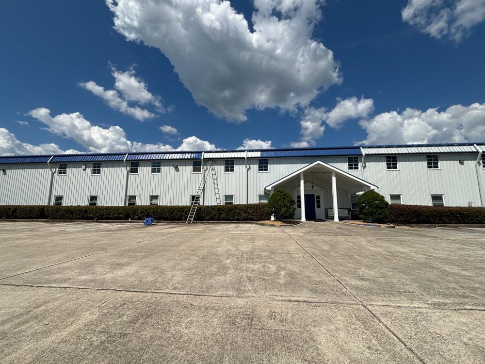 White building with blue roof and clouds, in a clear sky.