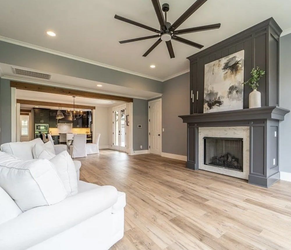 Bright living room with white sofa, fireplace, and open kitchen.