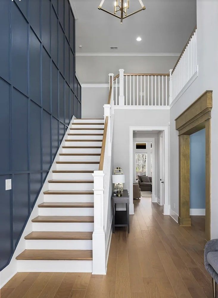 Staircase with blue wall paneling and wooden floors leading to an upper level and an entryway.