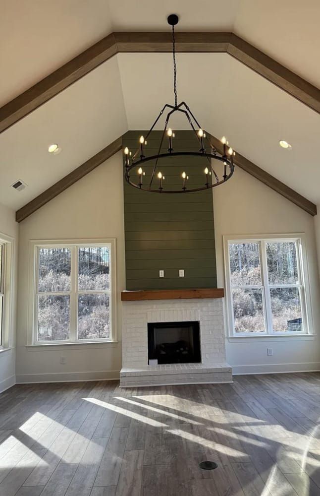 Living room with a vaulted ceiling, fireplace, windows, and a chandelier.