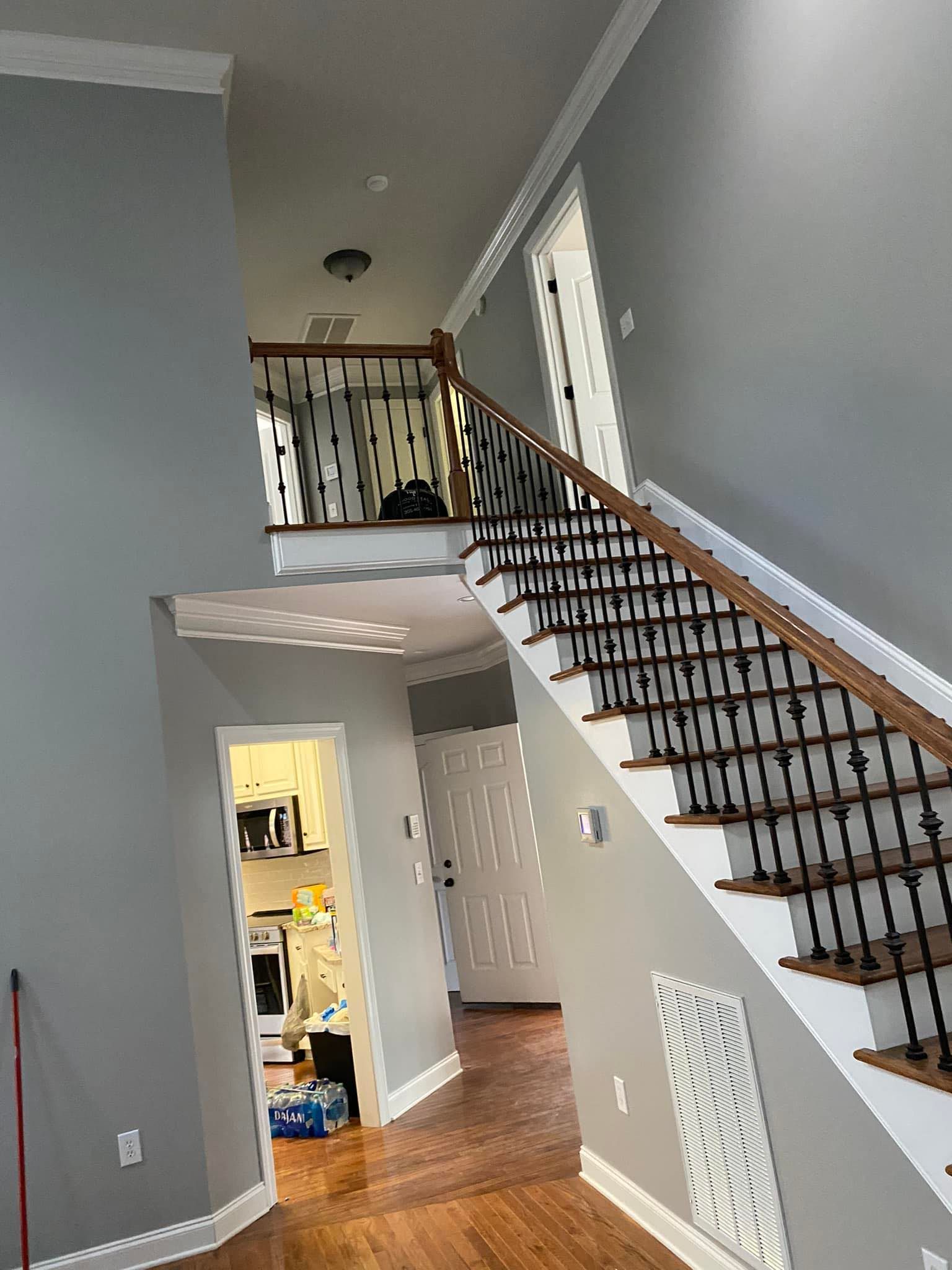 Interior view of a two-story foyer with stairs, wood floors, and gray walls.