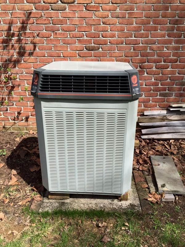 Outdoor air conditioning unit against a brick wall.