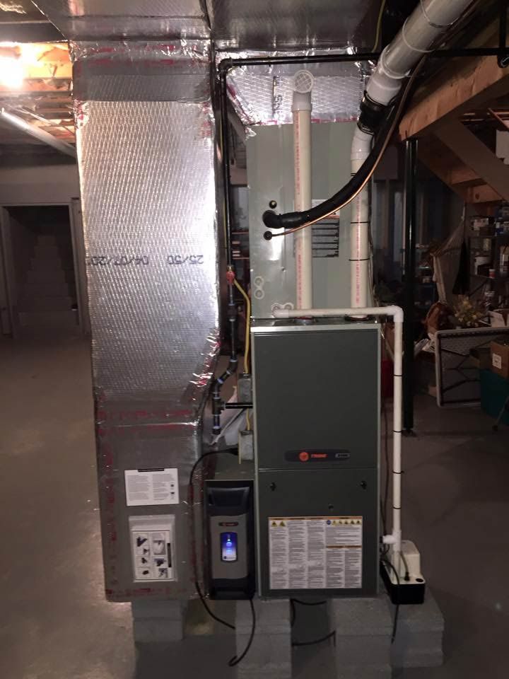 Furnace and ductwork in a basement. The unit is grey and white. Aluminum foil insulation is visible.