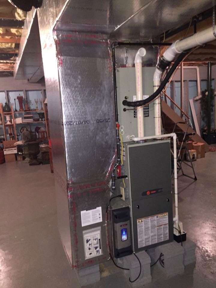 Furnace and ductwork in a basement. Silver metal ducting, gray furnace, and white PVC pipes are visible.