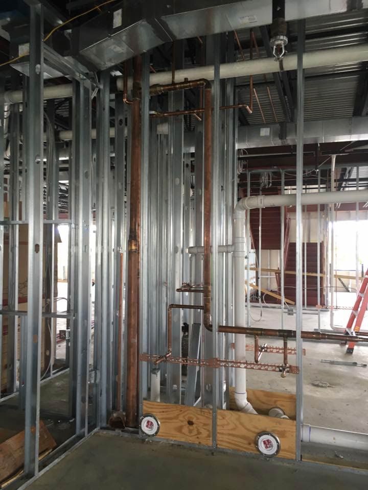 Metal pipes and framing in a building under construction. Copper pipes are prominent, along with a fire sprinkler.
